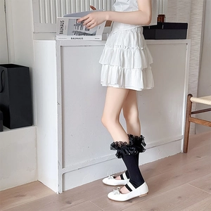 Close-up of black Lolita leg warmers featuring layered lace ruffles and white pearl beads