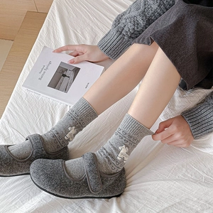 Detail of grey felt indoor slippers and mid-calf socks with white bear and heart patterns