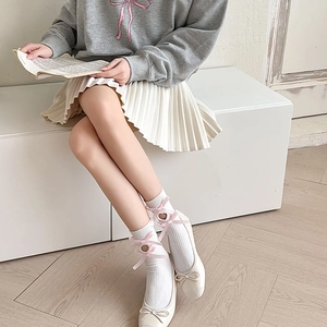 Detail of white ribbed mid-calf socks with pink silk bows and heart-shaped cutouts