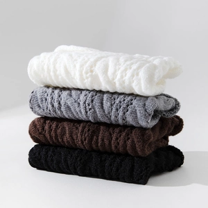 Close-up of cable knit leg warmers in white, grey, brown, and black winter colors