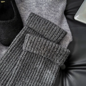Close-up of dark grey ribbed knit leg warmers with speckled texture on black leather