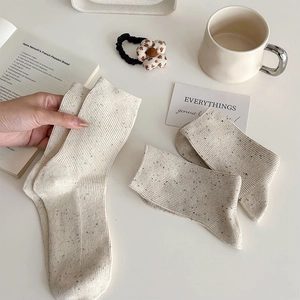 Close-up of cream ribbed knit mid-calf socks with colorful neps and soft cotton texture