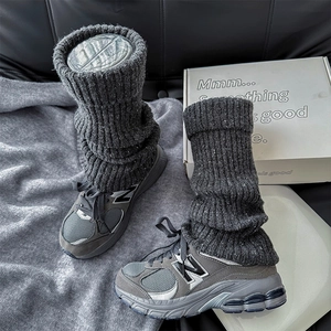Detail of thick dark grey ribbed knit leg warmers paired with mesh retro sneakers