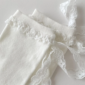 Close-up of white ribbed cotton socks featuring delicate lace edges and long ribbons