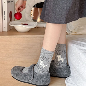 Close-up of cozy grey Mary Jane felt slippers and socks with white horse and heart patterns