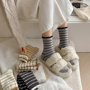 Detailed view of cozy striped coral fleece socks paired with fluffy white plush slippers