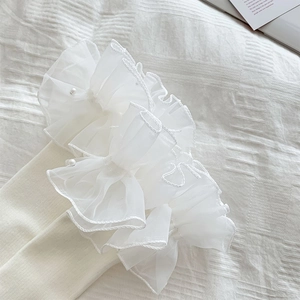 Close-up of white Lolita leg warmer with layered organza ruffles and pearl beads