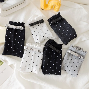 Détail de bordure à volants et nœuds métalliques sur chaussettes à pois tricotées