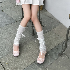 Close-up of pink satin ballet flats and white knit leg warmers with ribbon lacing