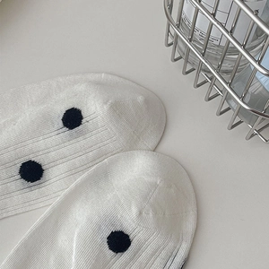 Detail of white cotton socks with black polka dots and vertical stripe texture