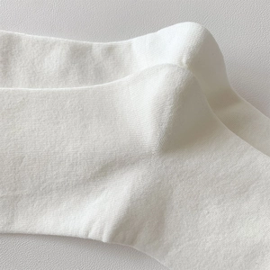 Macro shot of white knitted cotton socks showing breathable texture and durable heel stitching