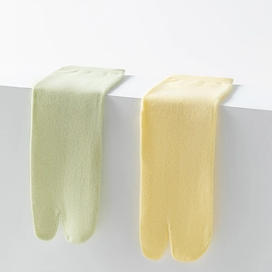 Close-up of light green and yellow tabi socks with split-toe design in soft cotton knit