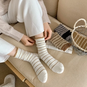 Close-up of striped fleece socks in various colors on a cozy home sofa setting