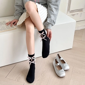 Detail of black Lolita mid-calf socks with pink ribbon bows and hollow knit design