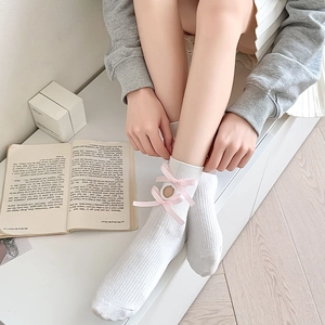 Detail of white ribbed calf socks featuring pink satin bows and hollow out ornaments