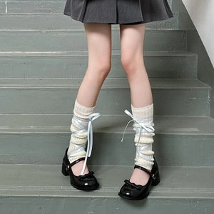 Close-up of balletcore knit leg warmers with blue ribbon bows and Mary Jane shoes