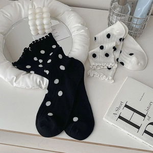 Detailed view of ruffled dot socks in black and white with minimalist home decor props