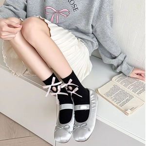 Detail of black mid-calf socks with pink silk bow and lace-up cutouts on the side