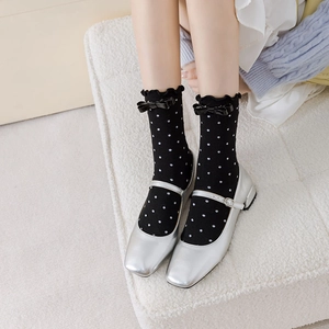 Détail de chaussures Mary Jane argentées avec chaussettes à pois noires et nœuds élégants