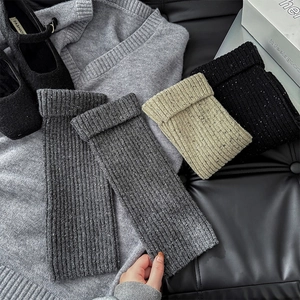 Detailed texture of rib-knit leg warmers in dark gray and beige mixed yarn