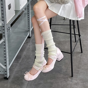 Detail of balletcore knit leg warmers with ribbons paired with pink Mary Jane shoes