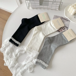 Detail of Lolita style crew socks featuring white lace trim and bow ribbons in three colors