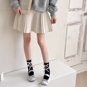 Detail showing white hollowed mid-calf socks with pink satin bows and pleated skirt