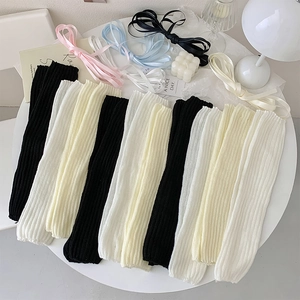 Ballet style knitted leg warmers with ribbons in black white and beige flat lay