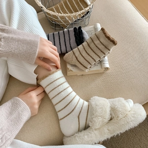 Thick striped knit crew socks in warm autumn tones shown in a cozy home setting