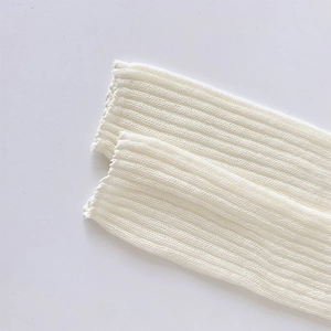 Close-up of white ribbed knit ballet leg warmers with delicate vertical texture