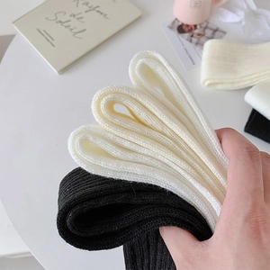 Detailed close-up of ribbed knit texture on black and cream ballet style leg warmers