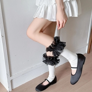 Detail of Lolita black organza leg ruffles with white faux pearls on white stockings