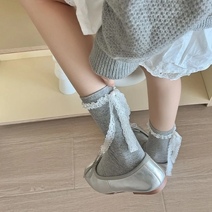 Close-up of gray calf socks with white lace trim and elegant long ribbon bow details