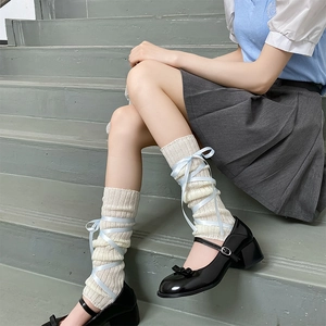 Detail of ballet style cream knit leg warmers with crossed light blue silk ribbons