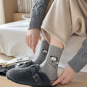 Detail of grey crew socks with puppy motif and felt clogs in a cozy home setting