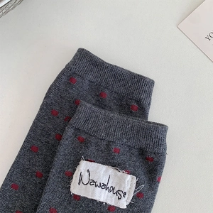 Gros plan de chaussettes en maille grise à pois rouges avec étiquette en tissu