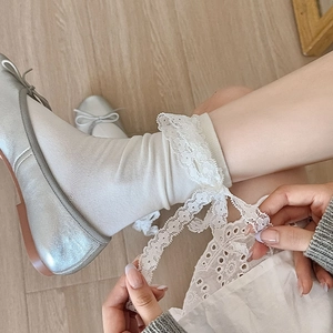 Detailed macro view of white lace mid-calf socks with delicate ribbon bow and silver ballet flats