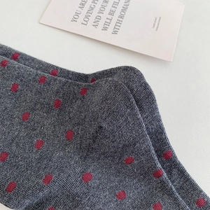 Détail de chaussettes en maille grise à pois rouges avec étiquette en tissu