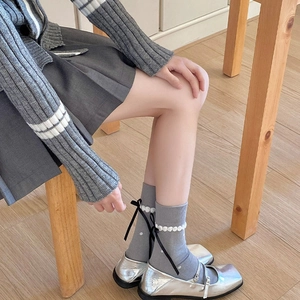 Detail of grey calf socks with pearl beads and a black silk ribbon bow on the back