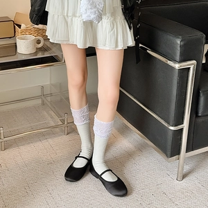 Close-up of white lace trim socks with purple floral detail paired with Mary Jane shoes