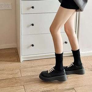 Detail of black platform loafers with off-white laces and thick chunky sole
