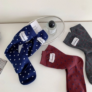 Gros plan de chaussettes en tricot à pois avec étiquettes tissées en bleu, bordeaux et gris