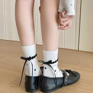 Close-up of white knit socks with black velvet bows and polka dots on Mary Jane shoes