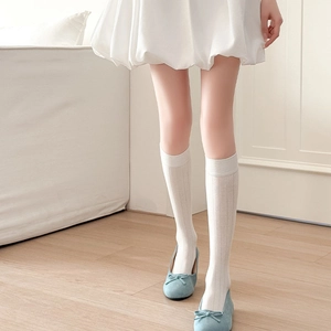 Détail de chaussettes hautes blanches à rayures verticales avec mocassins à nœud et jupe