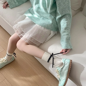 Close-up of mint green knit sweater, lace skirt, and bow socks for a sweet college style