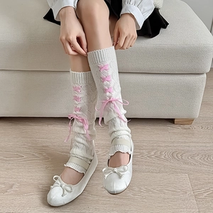 Detail of white ribbed leg warmers with pink lace-up ribbons and sweet bow accents