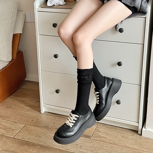 Detail of black platform leather shoes with beige laces and knitted calf socks style