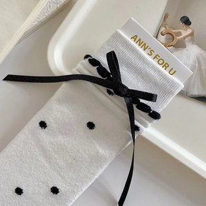 Detail of white mid-calf socks with black polka dots and silk ribbon bow accent