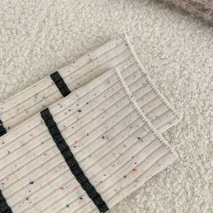 Close-up of striped knit socks with colorful speckles on warm faux fur background
