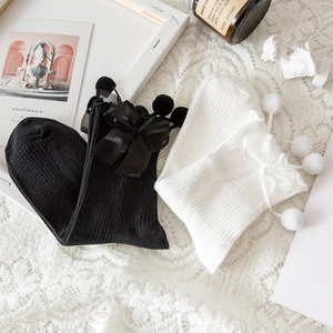 Dettagli di calze Lolita con volant, fiocchi di seta e pompon in bianco e nero